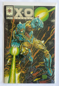 A comic book, X-O Manowar issue #2, featuring a dynamic illustration of a blue and gold armored superhero on a black space background with green energy effects. The comic is housed in a clear protective sleeve.